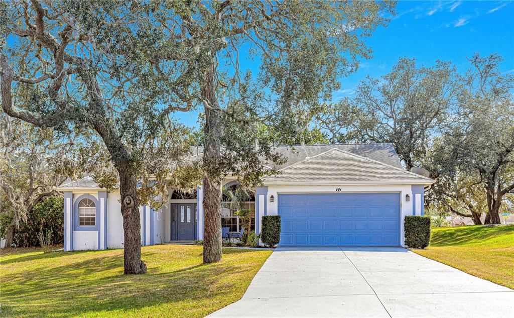 a front view of a house with a yard garage and large tree