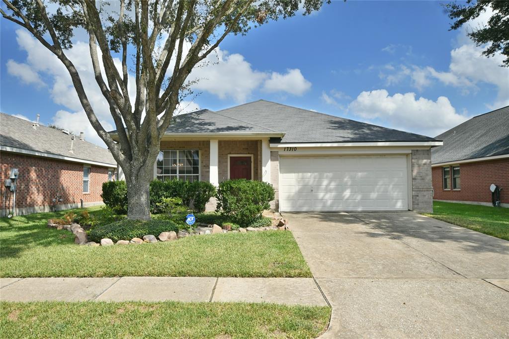 Charming single-story home with a well-maintained front yard featuring a mature tree, an inviting entrance, and an attached two-car garage.