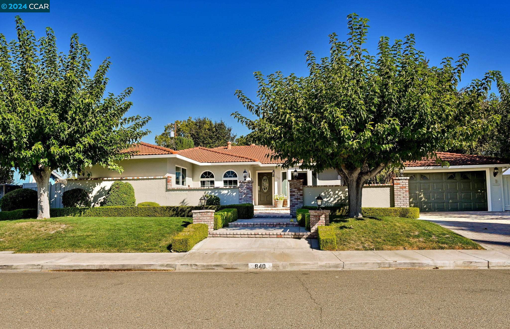 a front view of a house with a garden and trees