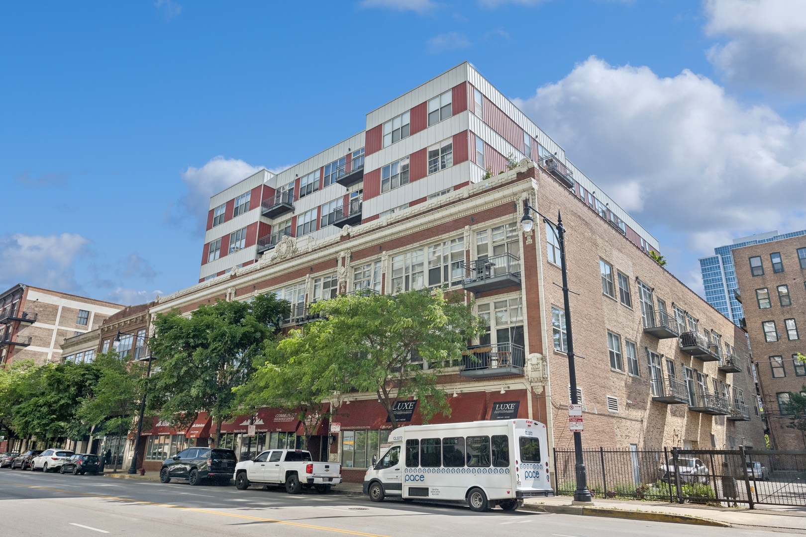 a front view of a building with lot of cars and trees