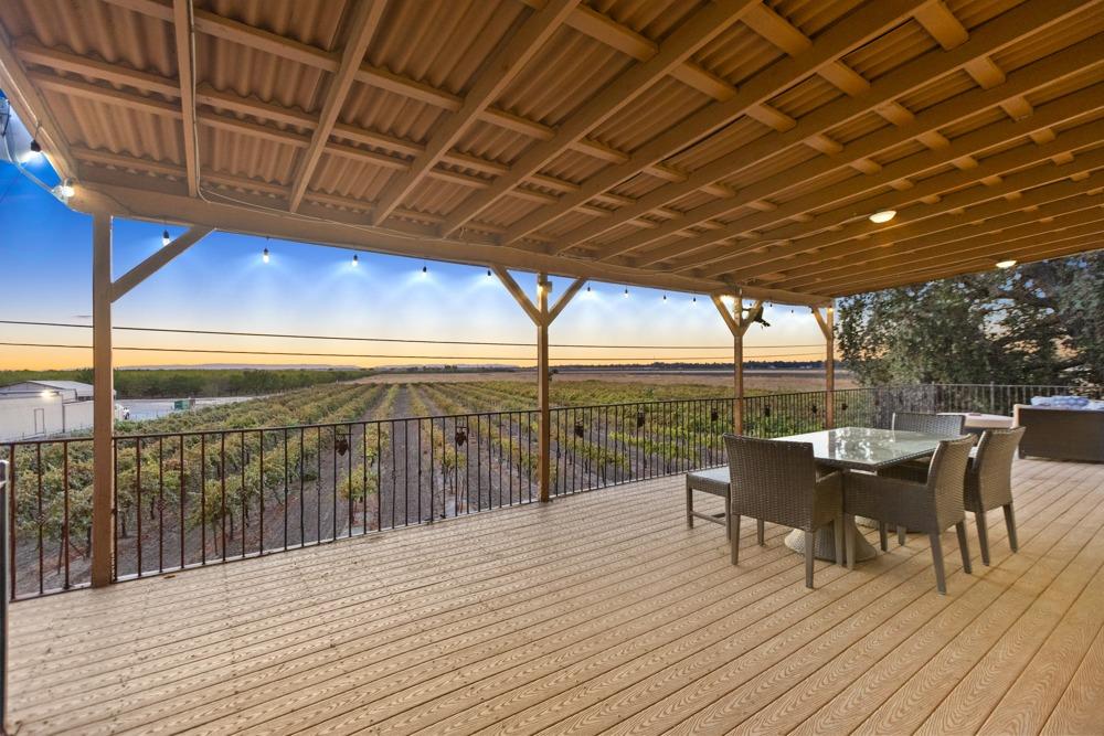 a view of a roof deck with table and chairs a barbeque with wooden floor and fence