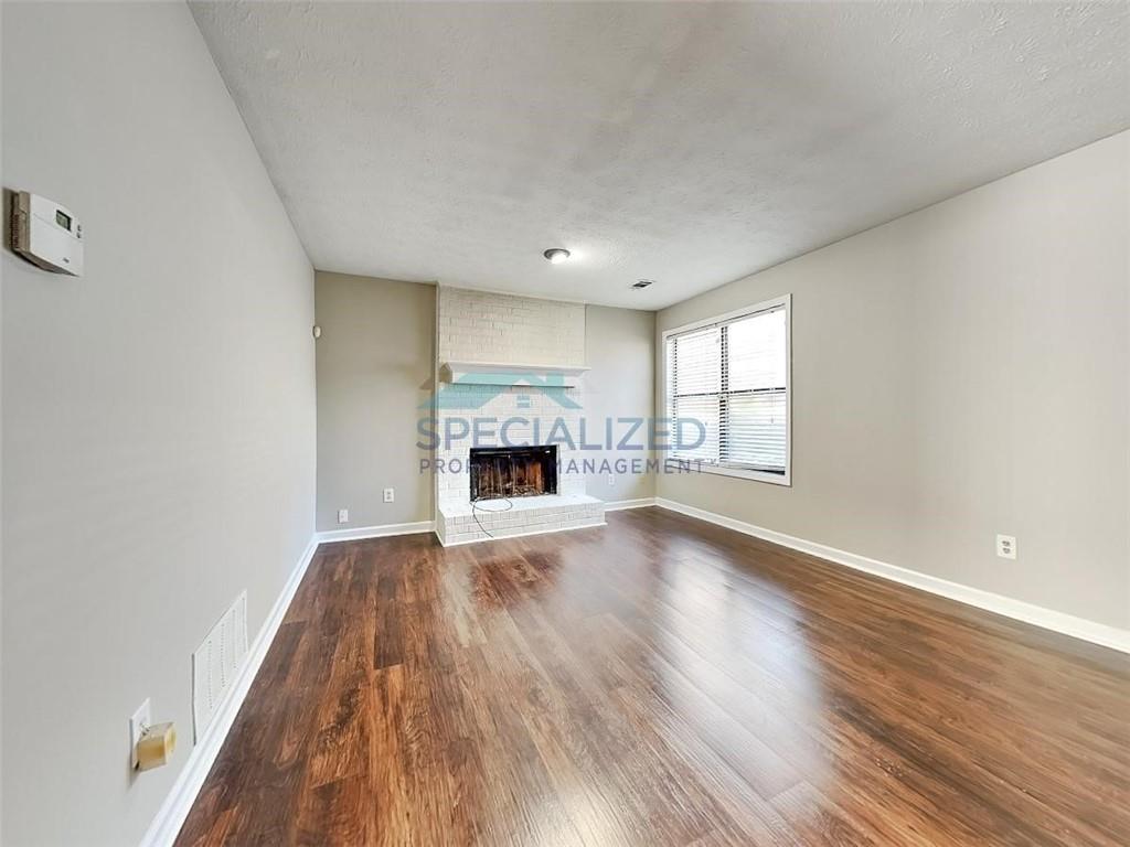 an empty room with wooden floor fireplace and windows