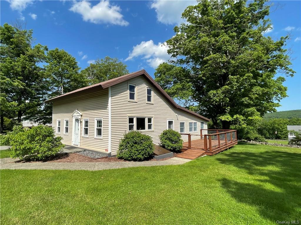 Back of property featuring a lawn and a wooden deck