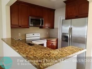 a kitchen with stainless steel appliances granite countertop a stove top oven microwave and refrigerator