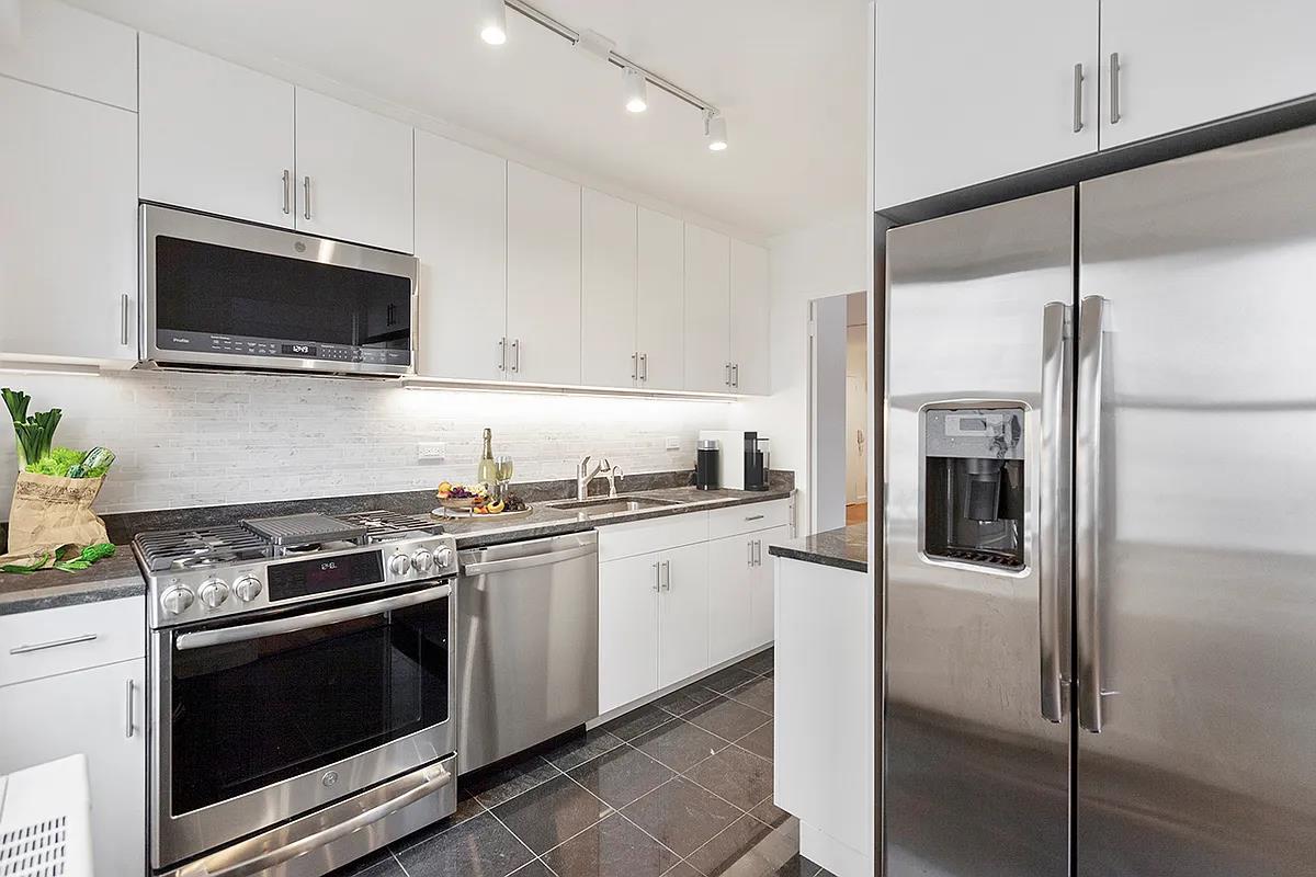 a kitchen with stainless steel appliances white cabinets and a stove top oven