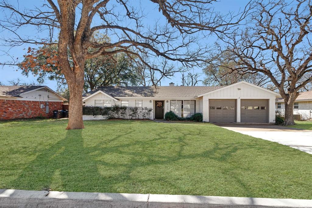 a front view of a house with a garden and trees