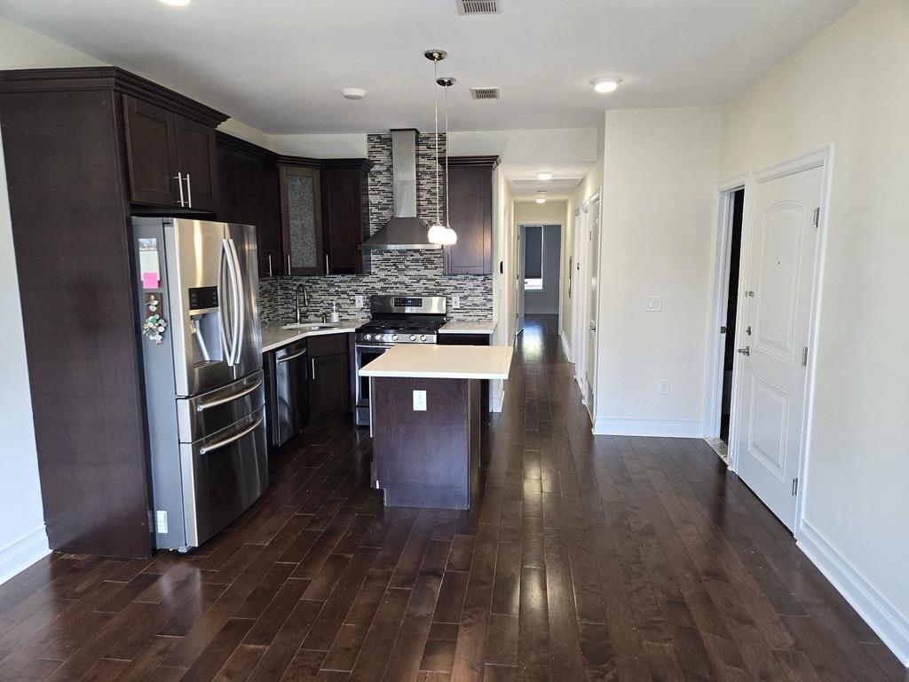 a kitchen with kitchen island wooden floors appliances and cabinets