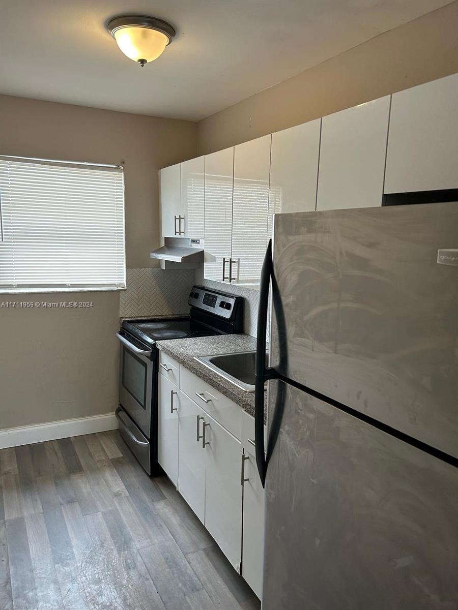 a kitchen with granite countertop a sink cabinets stainless steel appliances and a counter space