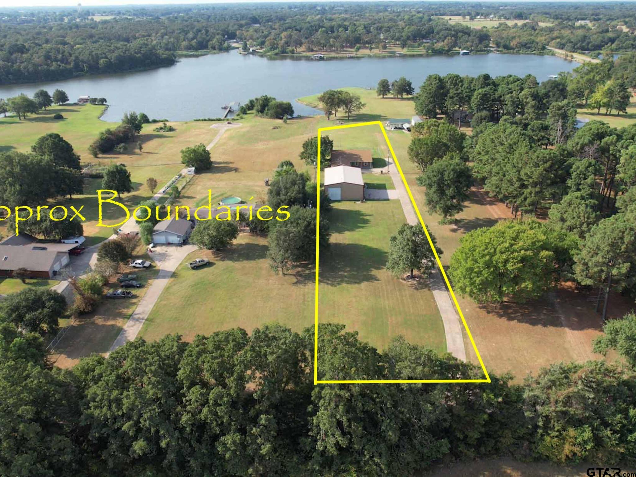 a view of a lake with a yard and large trees