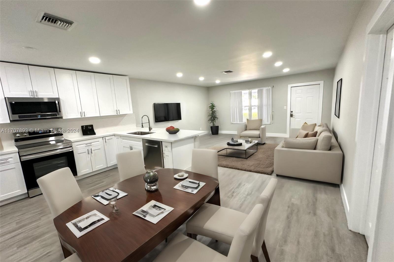 a living room with couches and kitchen view with wooden floor