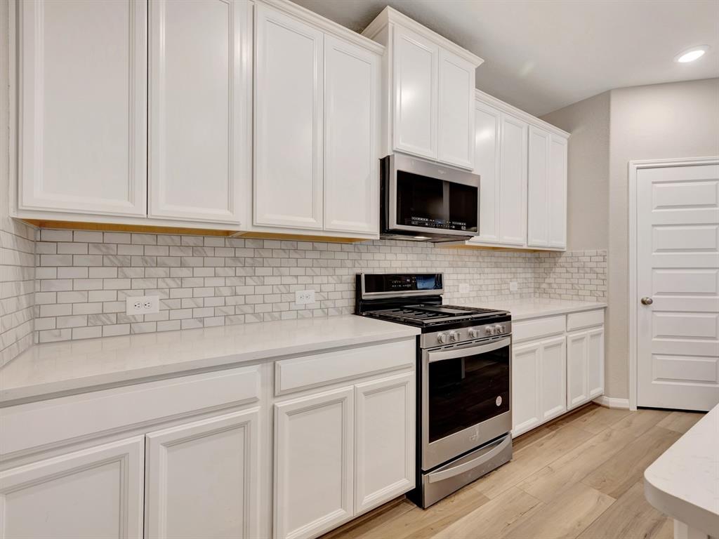 a kitchen with white cabinets and stainless steel appliances