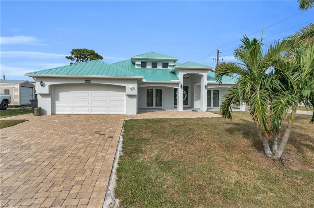 View of front of property with a front yard, french doors, and a garage