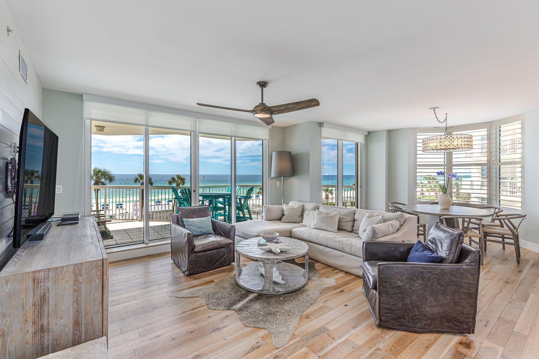 a living room with furniture large windows and wooden floor