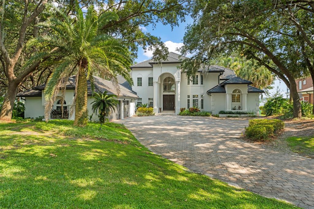 a view of a white house next to a yard with big trees