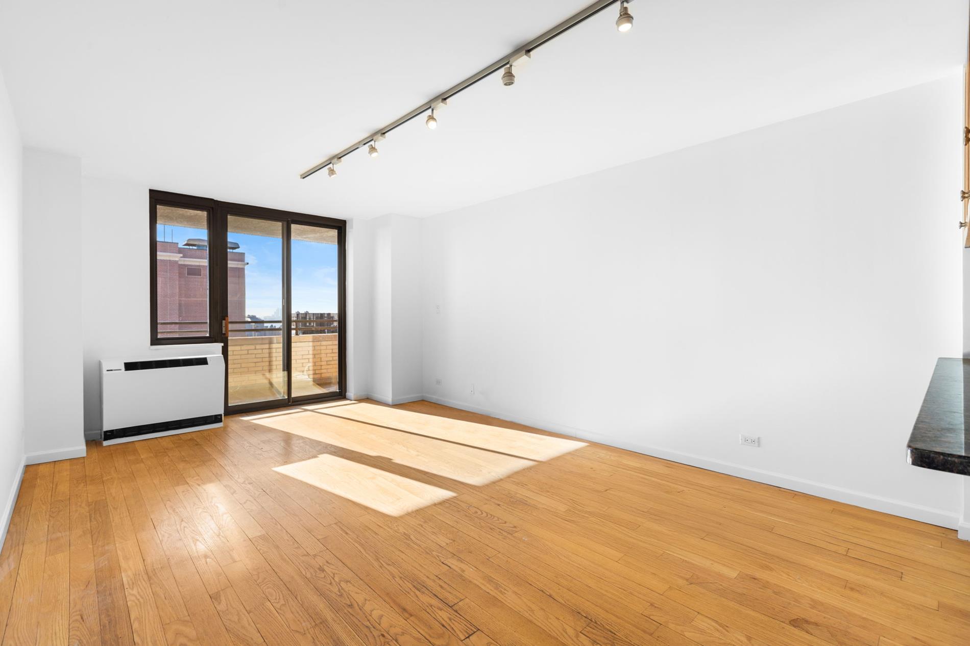 a view of an empty room with wooden floor and a window