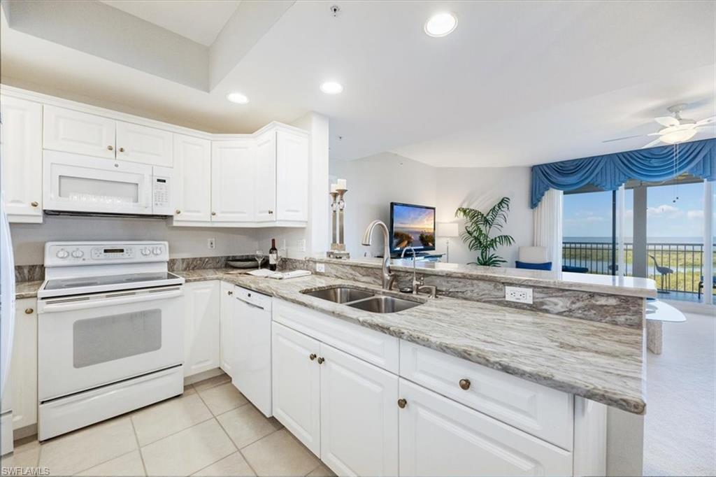 a kitchen with granite countertop white cabinets sink and stainless steel appliances