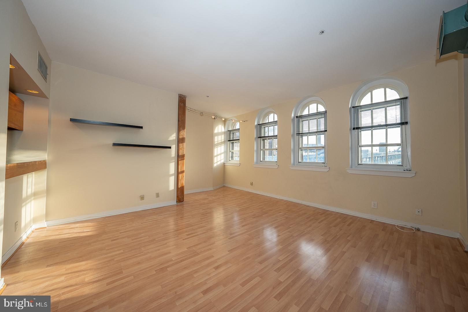 a view of an empty room with wooden floor and a window