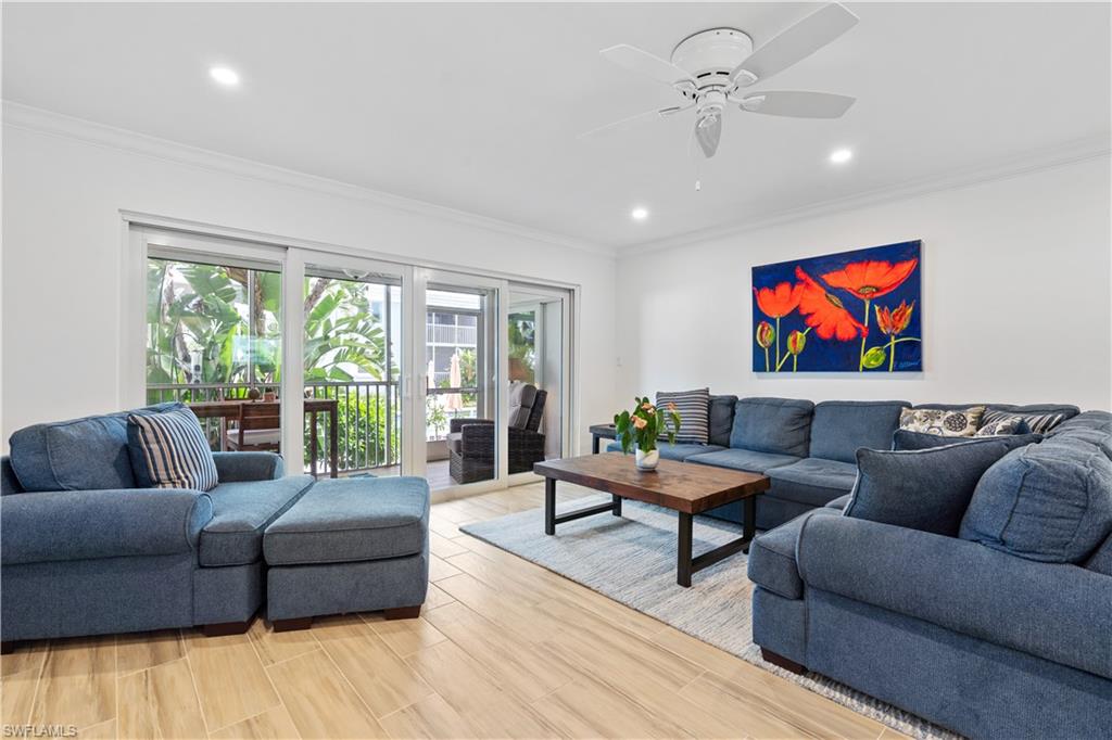 Living room with ceiling fan, crown molding, and light wood-type flooring