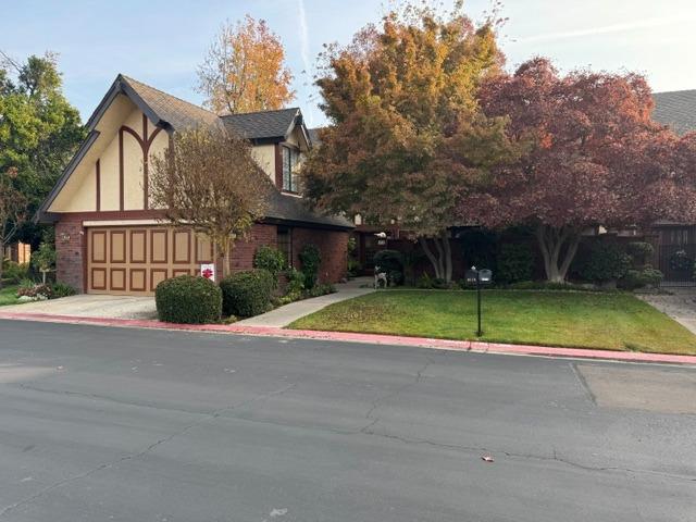 a view of a house with a small yard and a large tree