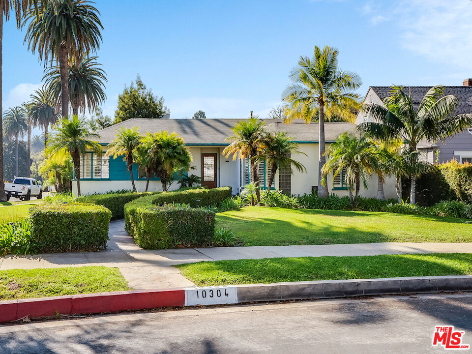 a view of a house with a yard and palm trees