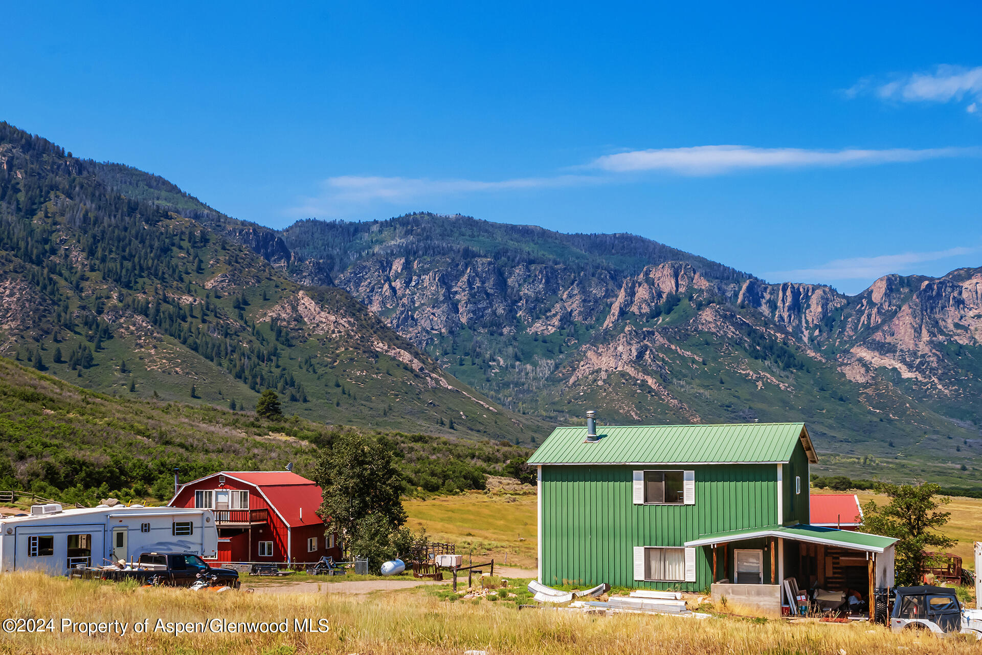 a front view of a house with a yard and mountain view in back