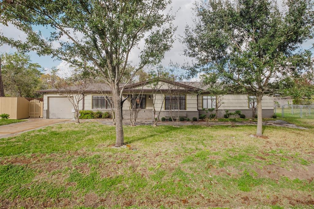 This charming single-story home features a welcoming facade with mature trees in the front yard, a well-maintained lawn, and a single-car garage. The exterior has a classic, cozy appeal, ideal for anyone looking for a peaceful neighborhood setting.