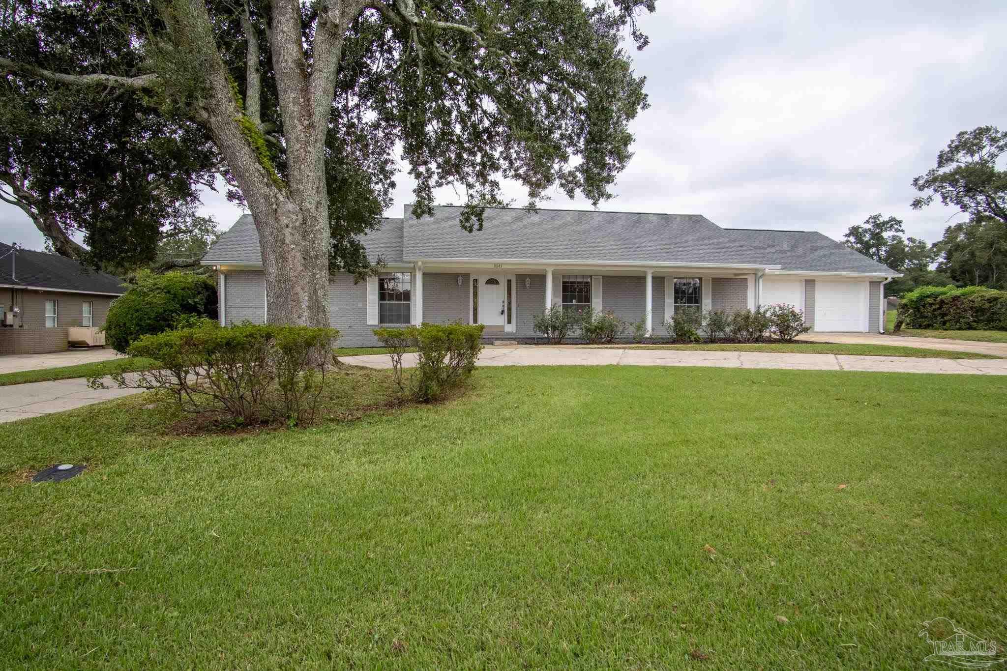 a front view of a house with a garden and trees