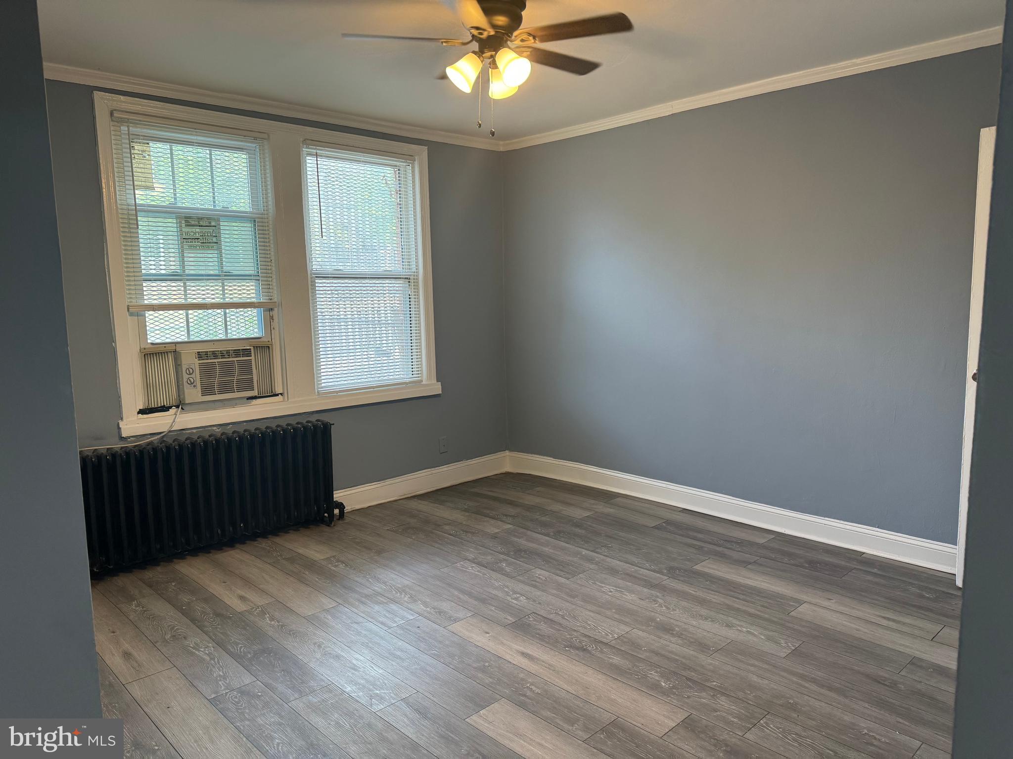 an empty room with wooden floor fan and windows