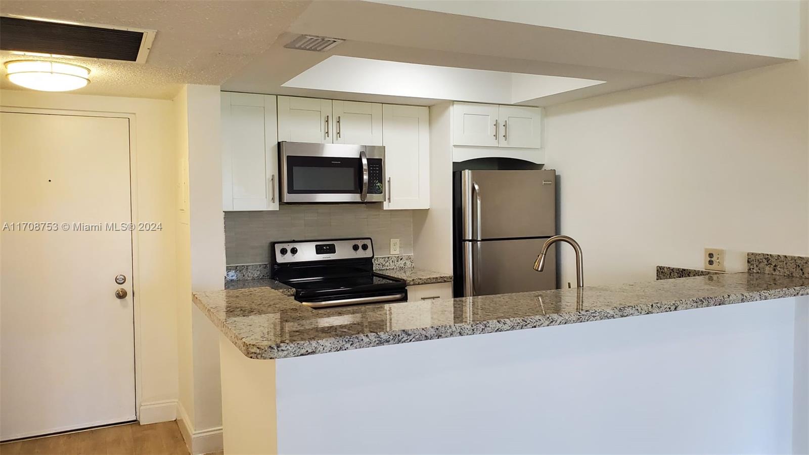 a kitchen with stainless steel appliances granite countertop a refrigerator a stove and a sink