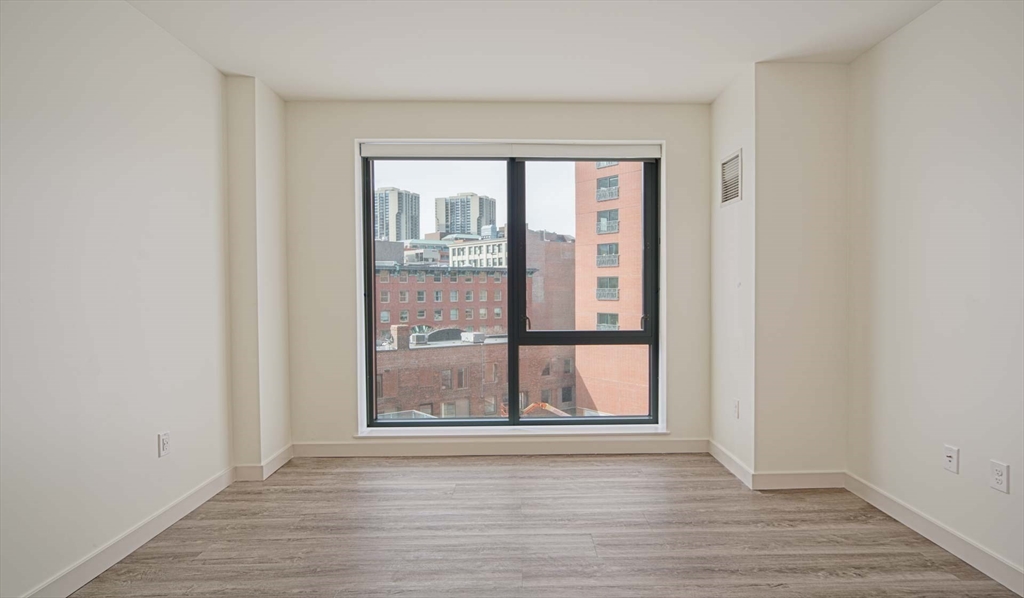 a view of an empty room with wooden floor and a window