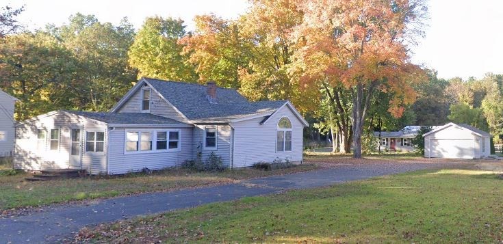 a view of a yard in front of a house with large trees