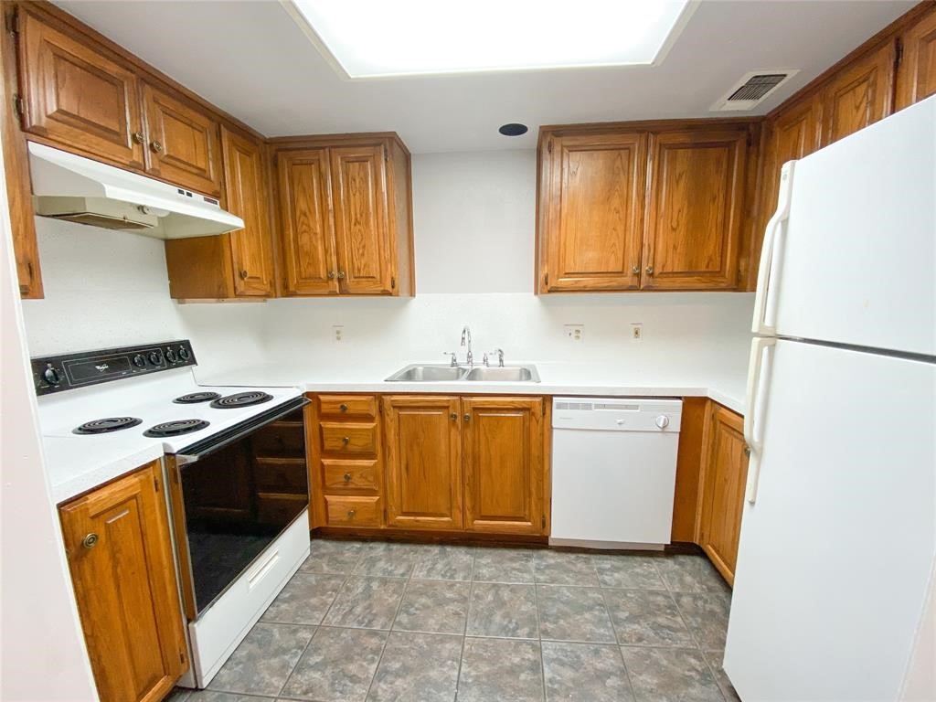 a kitchen with granite countertop a refrigerator a sink a stove and white cabinets