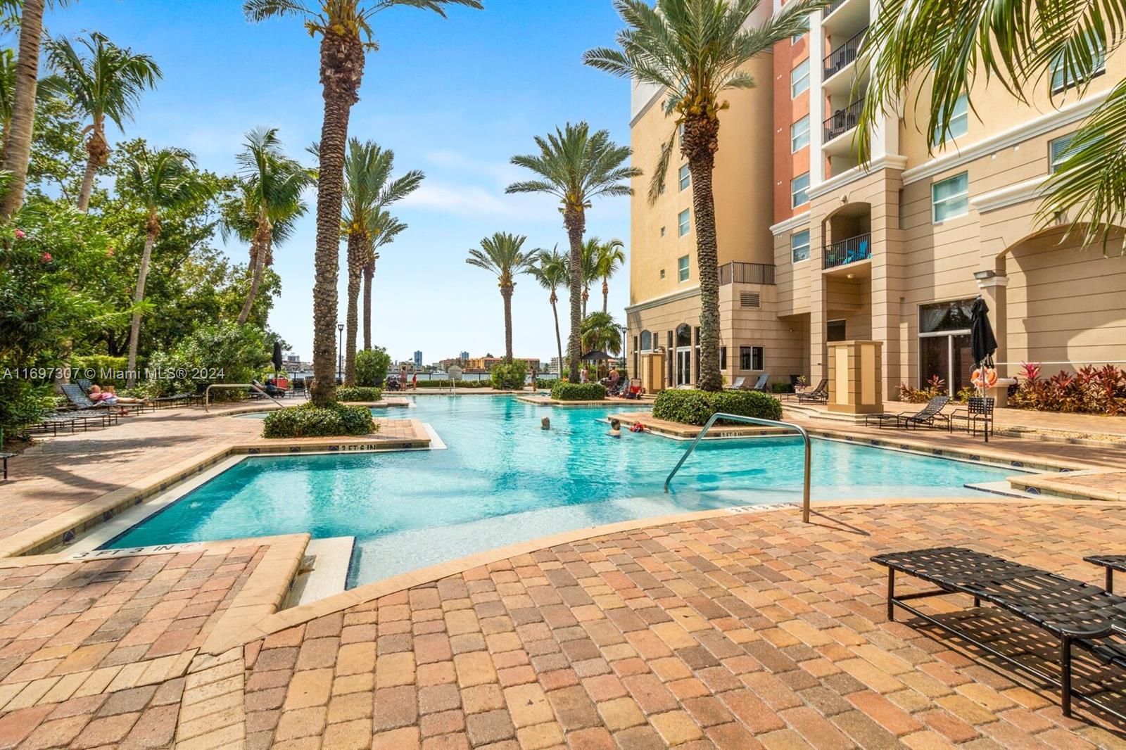 a view of a swimming pool with a lounge chair and palm trees