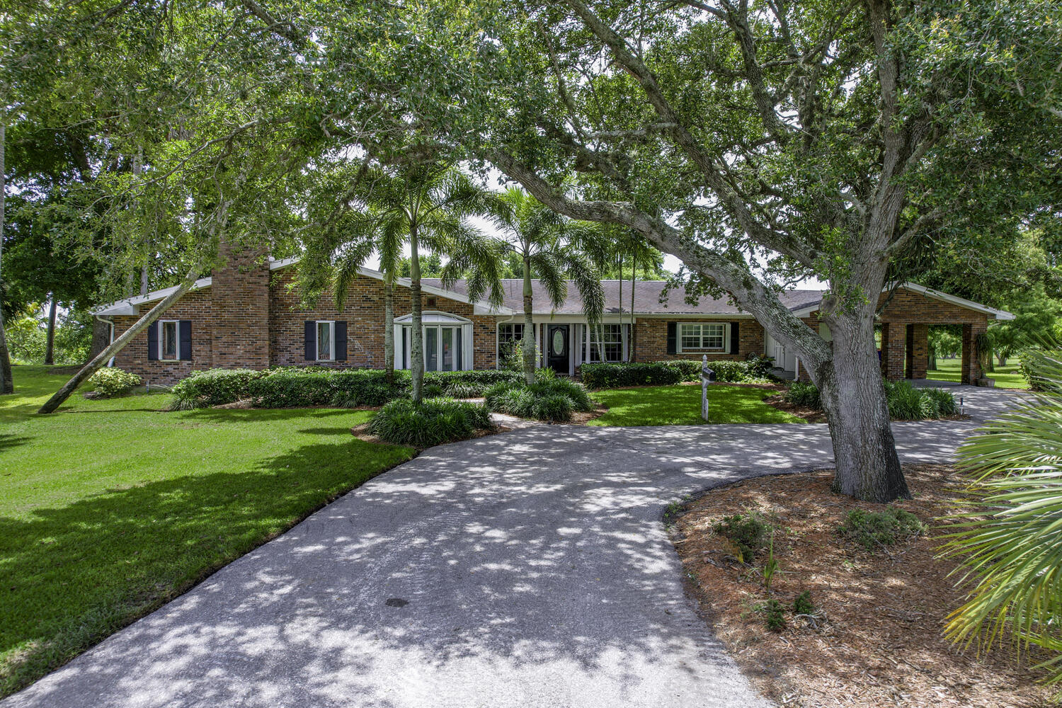 a front view of a house with a garden and trees