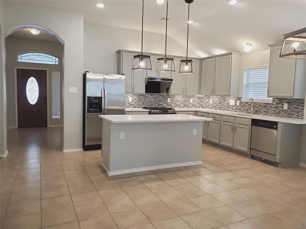 a kitchen with kitchen island granite countertop a stove a sink and a refrigerator