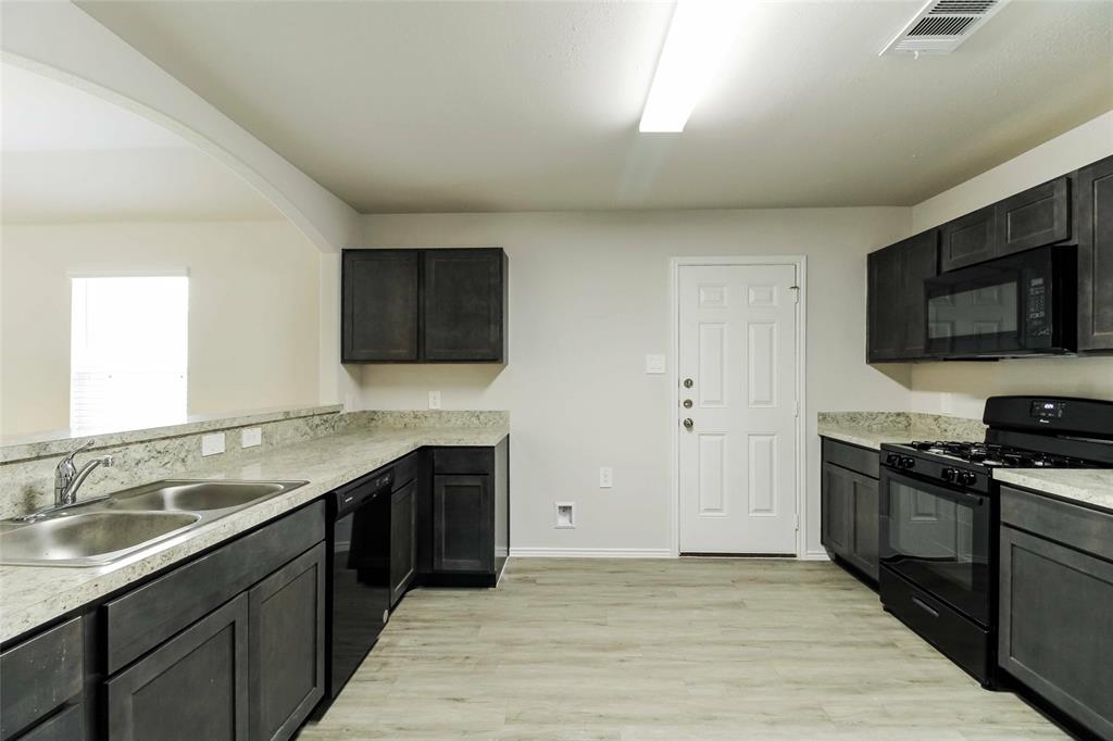 a kitchen with stainless steel appliances granite countertop a sink and a stove top oven with wooden floor