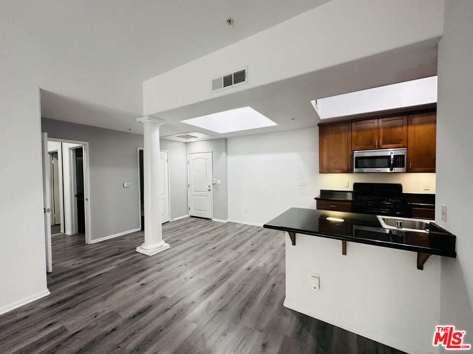 a kitchen view with wooden floor and electronic appliances