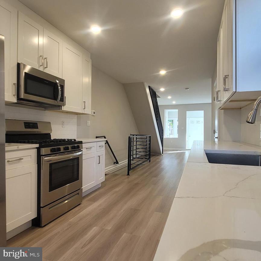 a kitchen with stainless steel appliances a stove a microwave and white cabinets