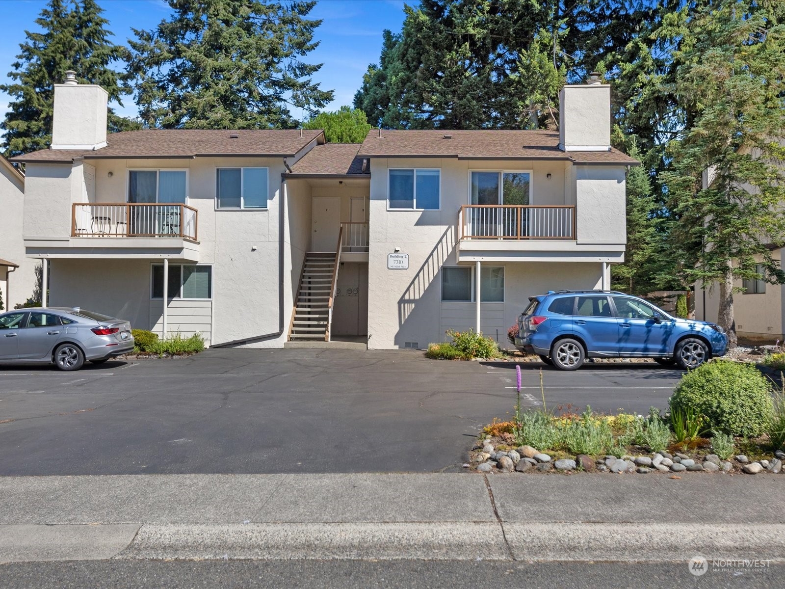 a front view of a house with a garden and parking