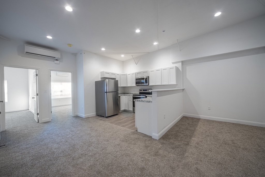 a view of a kitchen with refrigerator and white cabinets