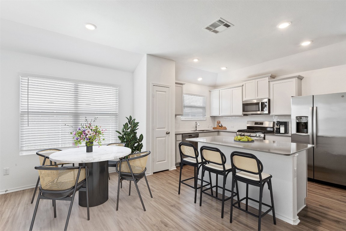 a kitchen with kitchen island a dining table and chairs