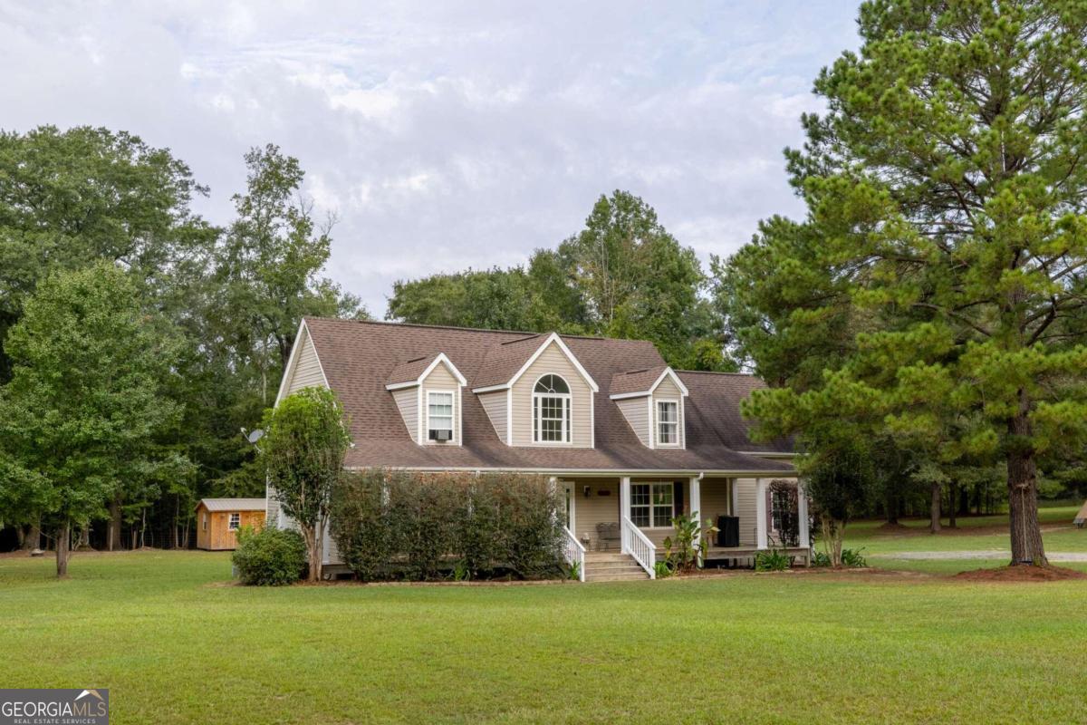 a front view of a house with garden and trees