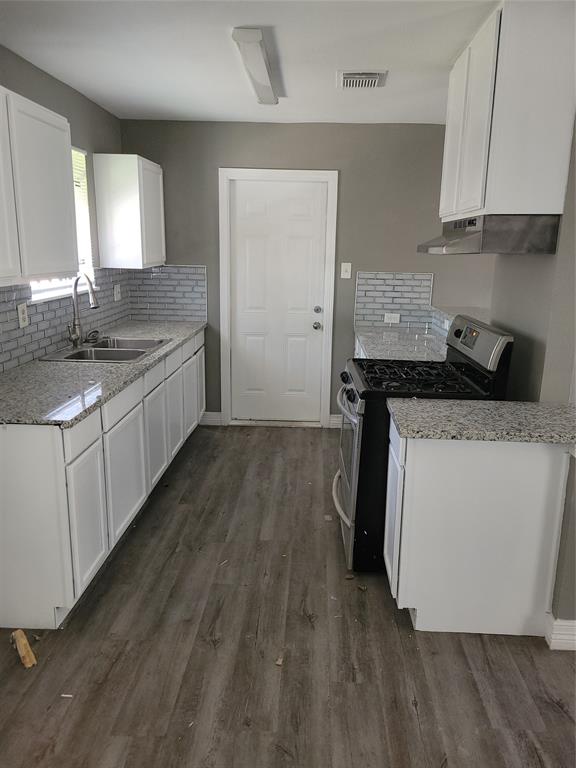 a kitchen with a sink and wooden floor