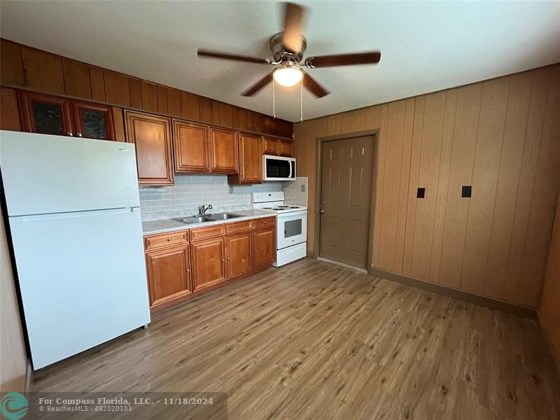 a kitchen with a refrigerator a stove top oven a sink and dishwasher with wooden floor