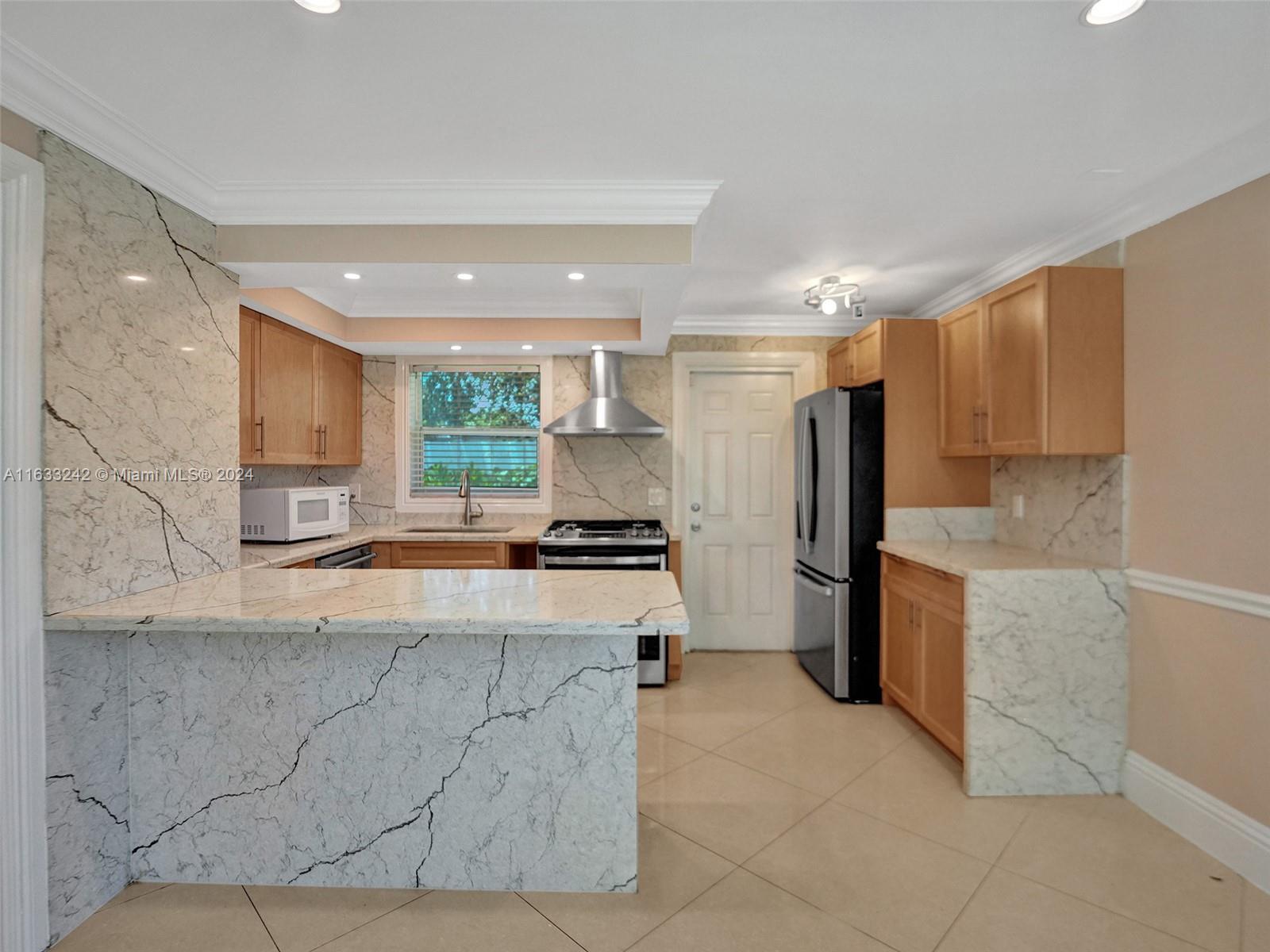 a large kitchen with kitchen island granite countertop a large counter top stainless steel appliances and cabinets