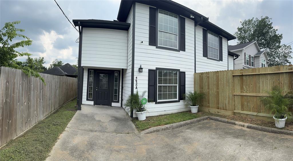 a view of a house with a small yard and wooden fence