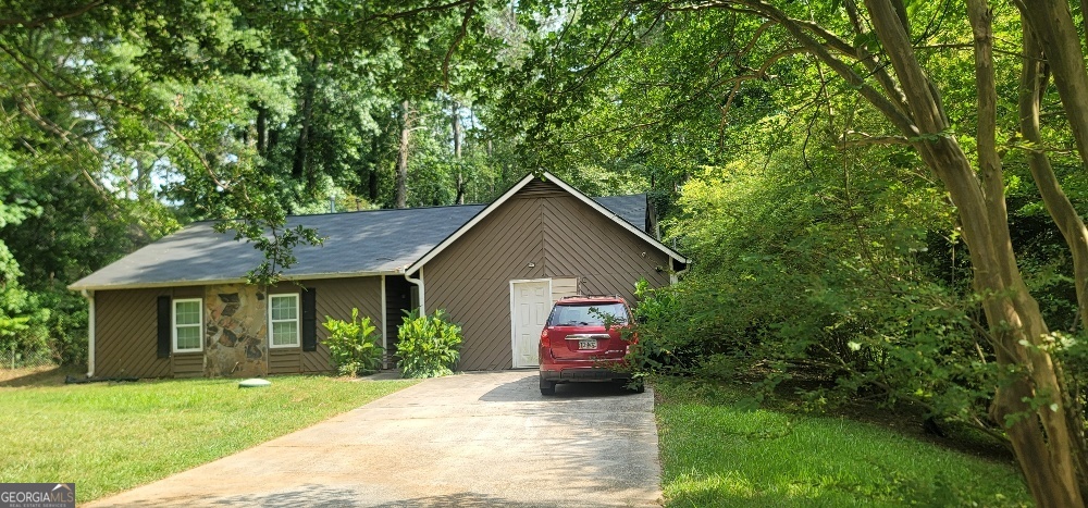 a view of a house with a yard plants and a large tree