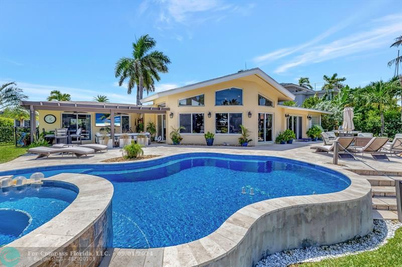 a view of swimming pool with outdoor seating and house in the background