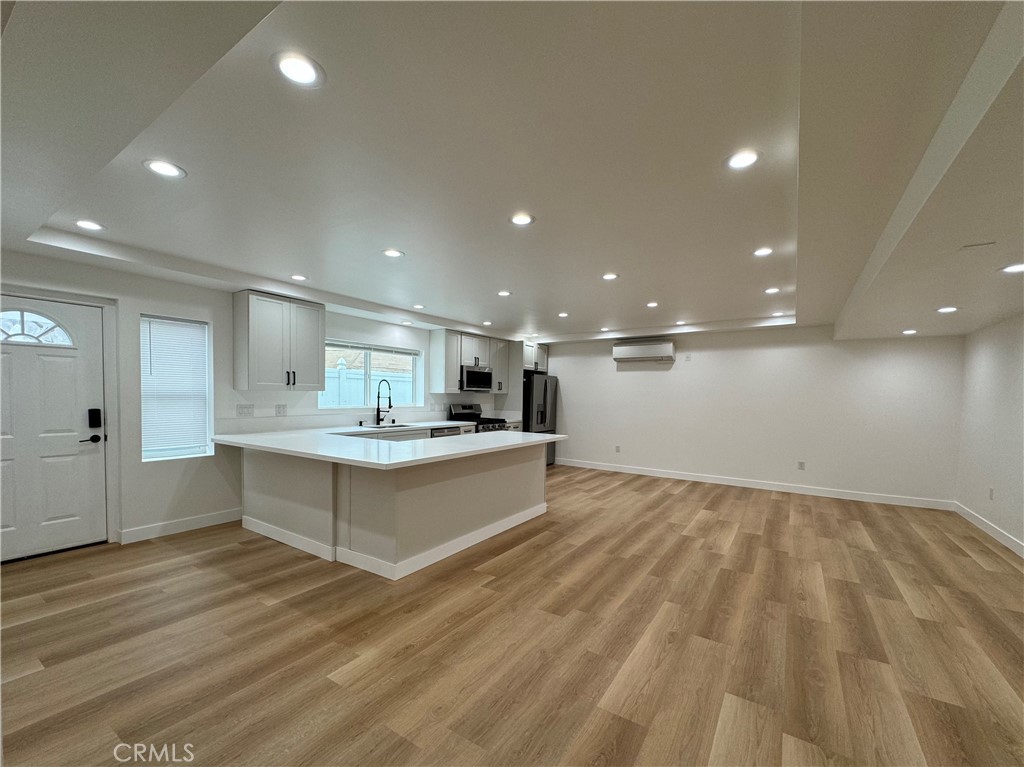 a large white kitchen with wooden floor and a sink