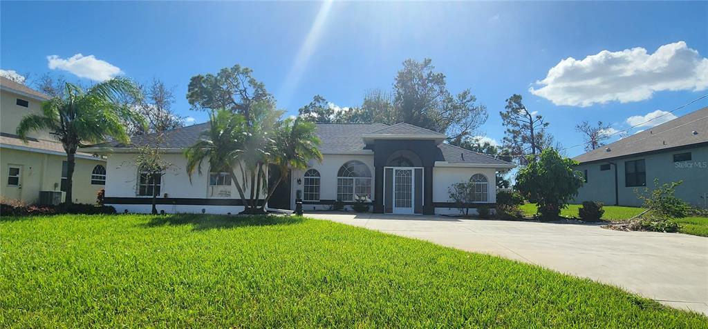 a front view of a house with a yard and palm trees